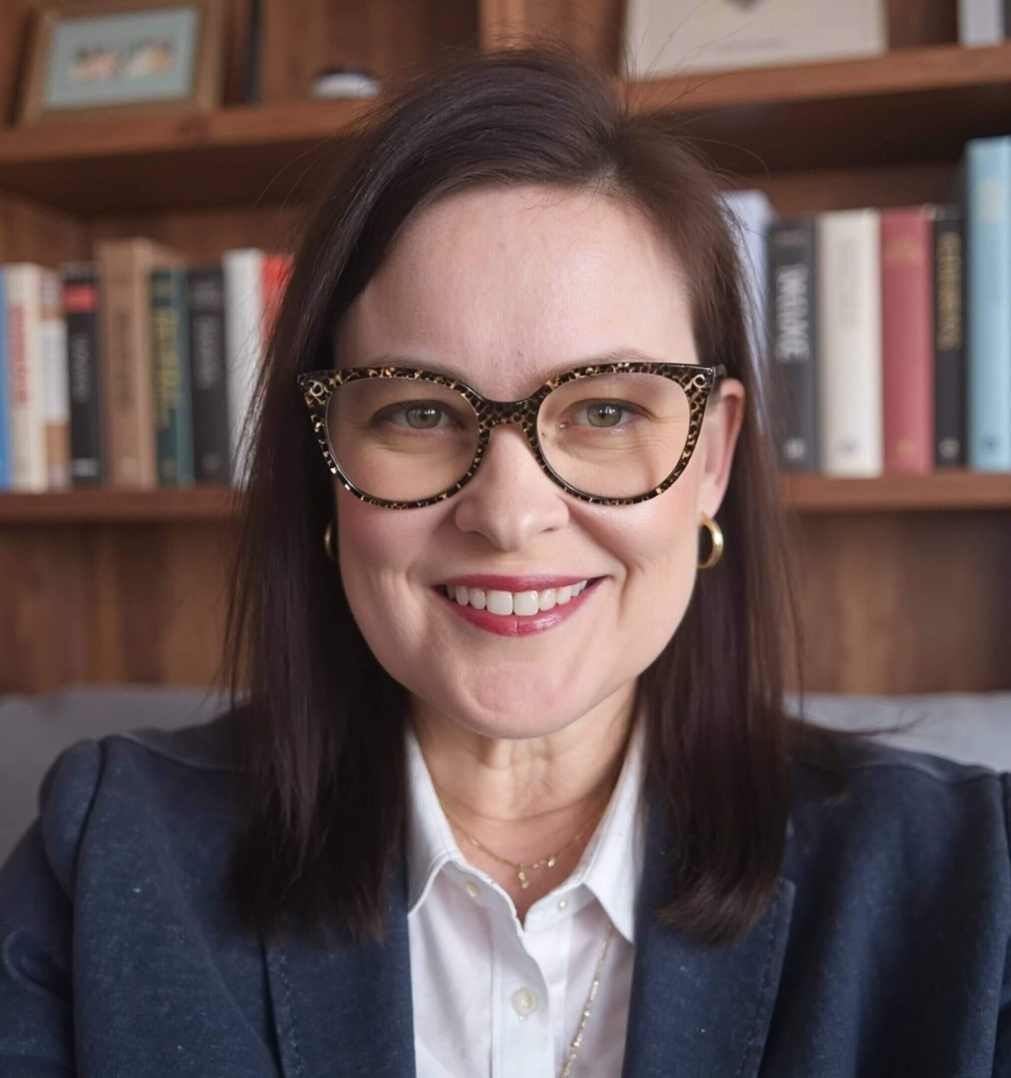 Smiling woman with glasses in a professional setting.